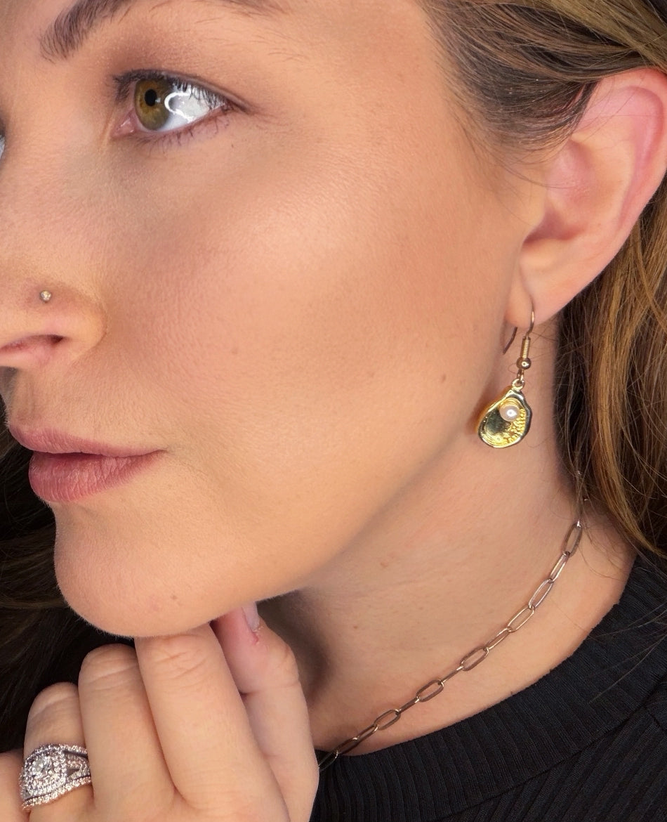 Close-up of 18k gold-filled oyster earrings with pearl detail, coastal-inspired jewelry