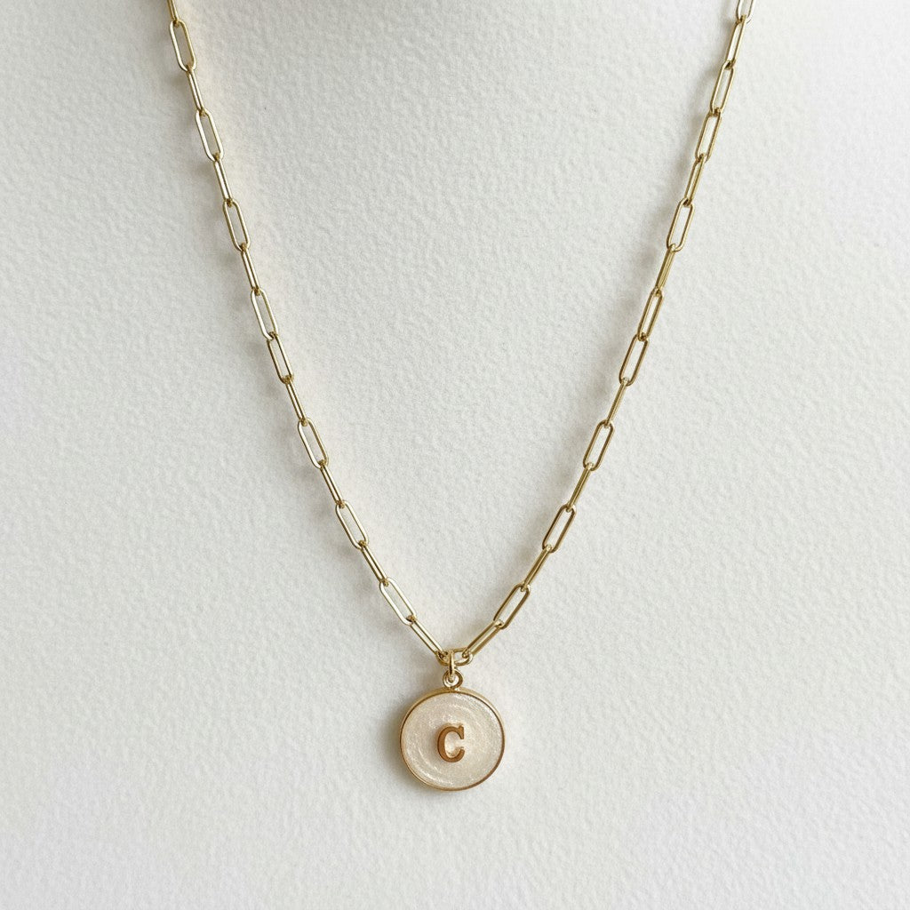 Close-up of pearl resin initial pendant on gold stainless steel necklace, personalized initial jewelry